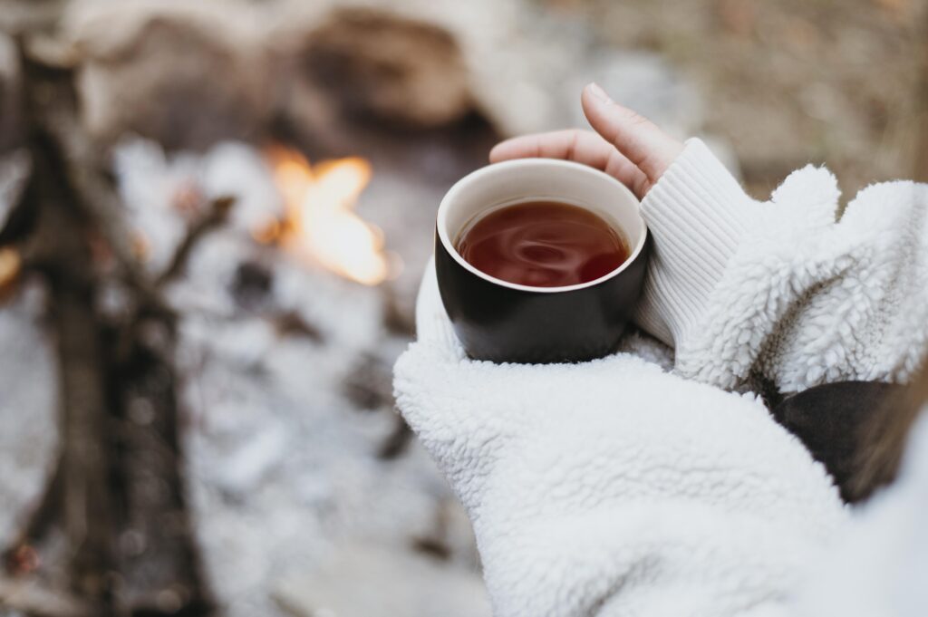 Person holding a warm cup of hot chocolate in the snow, reflecting and finding comfort during winter.